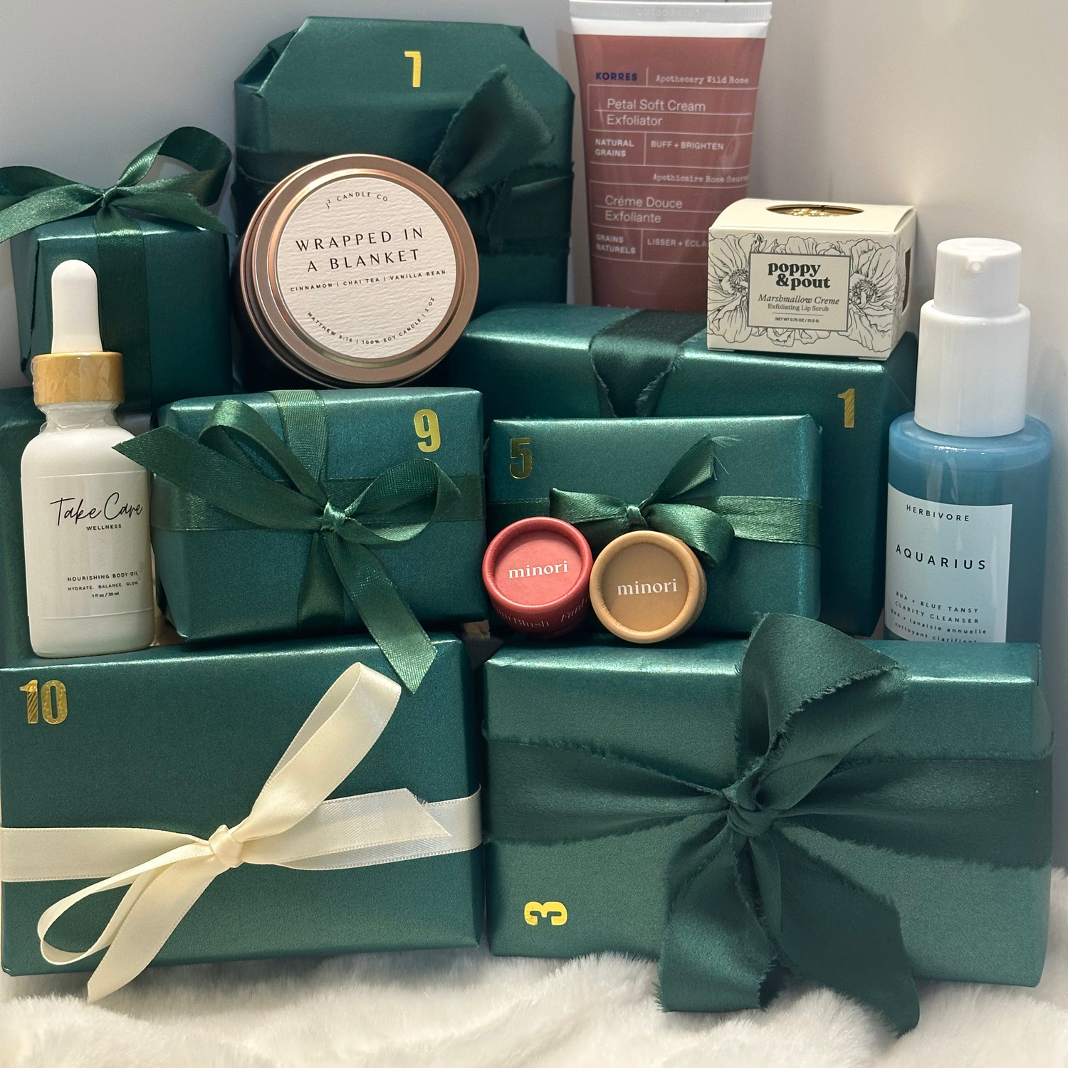 Collection of green gift boxes and skincare products on a light gray surface.